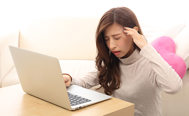 【頭痛】パソコンで見ながら頭痛を起こす女性